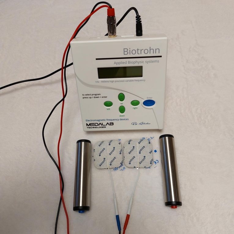 Ein Biotrohn-Gerät mit digitaler Anzeige, angeschlossenen Elektroden und Klebepads für die angewandte biophysikalische Therapie.